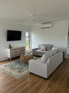 a white living room with a couch and a tv at Coastal Escape in North Coast
