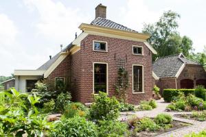 una vieja casa de ladrillo con un jardín delante de ella en De Wiede Blik, en Westerbroek