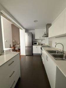 eine Küche mit weißen Schränken und einem Edelstahlkühlschrank in der Unterkunft La COlectiva HOME in Xàtiva