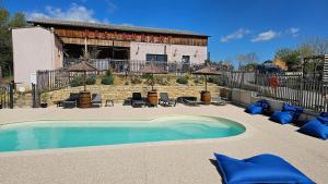 une piscine avec des coussins bleus devant un immeuble dans l'établissement L'Escale Occitane, à Alzonne 42 autres photos