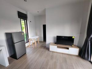 een woonkamer met een koelkast en een televisie bij Na-Tub House in Ban Nua