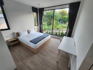 ein Schlafzimmer mit einem Bett und einem großen Fenster in der Unterkunft Na-Tub House in Ban Nua