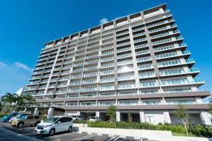 een groot gebouw met auto's geparkeerd op een parkeerplaats bij KAI Okinawa in Kitanakagusuku