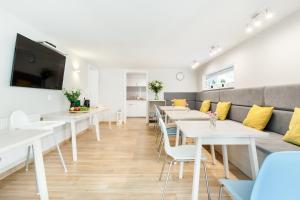 a dining room with white tables and yellow pillows at Villa Milla in Łeba