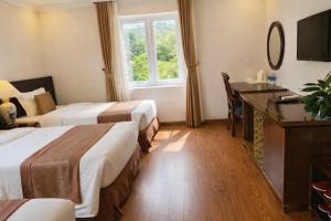 een hotelkamer met twee bedden en een bureau bij Adam Hotel Sa Pa in Sa Pa