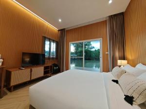 a bedroom with a large white bed and a television at Rivendale in Ban Gaeng Cho