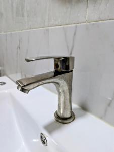 ein Waschbecken mit einem silbernen Wasserhahn in der Unterkunft Cozy Comfort Studio Central Muscat in Muscat