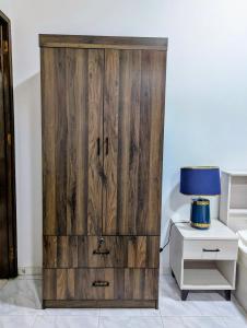 ein Holzschrank in einem Zimmer mit einer Lampe in der Unterkunft Cozy Comfort Studio Central Muscat in Muscat