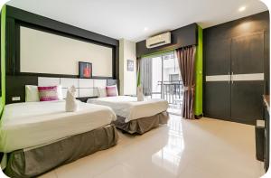 two beds in a hotel room with a window at Star House Patong in Patong Beach