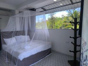 a bedroom with a canopy bed with a large window at Why Not Guset House Ella in Ella