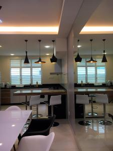 a kitchen with a bar with white chairs and lights at Shamrock Boutique Villa in Batu Ferringhi