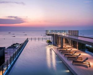 a building with a row of chairs on the water at Many Holiday The Base Condo in Pattaya