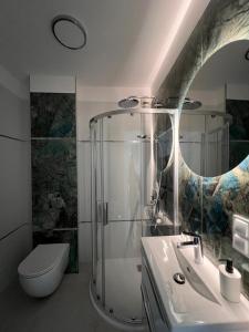 ein Badezimmer mit Dusche, Waschbecken und Toilette in der Unterkunft Apartamenty Wilenska in Słupsk