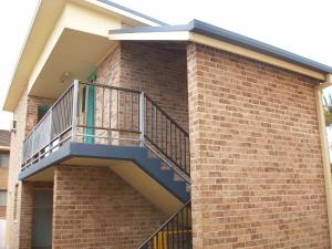 a brick building with stairs leading up to a balcony at John Oxley Motel in Port Macquarie
