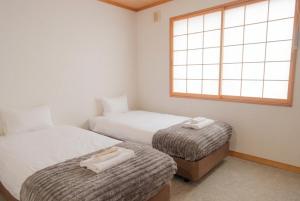 two beds in a small room with a window at The GAKUSUI in Hakuba