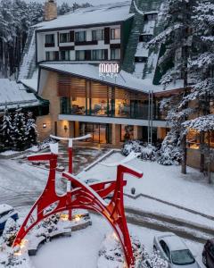 un vélo rouge dans la neige devant un bâtiment dans l'établissement Mona Plaza Zlatibor, à Zlatibor