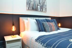 een slaapkamer met een bed met blauwe en witte kussens bij Manchester Ashton Suites in Ashton under Lyne