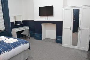 - une chambre avec un lit et une télévision au-dessus d'une cheminée dans l'établissement Manchester Ashton Suites, à Ashton-under-Lyne
