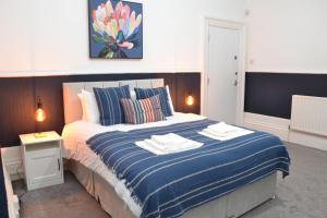 een slaapkamer met een groot bed met een blauwe deken bij Manchester Ashton Suites in Ashton under Lyne