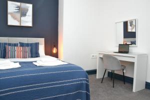 een slaapkamer met een bed en een bureau met een laptop bij Manchester Ashton Suites in Ashton under Lyne