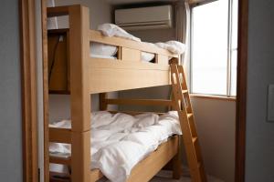 ein Etagenbett aus Holz in einem Zimmer mit Fenster in der Unterkunft ROTAN東本町 Omura in Matsue