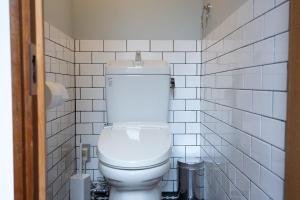 eine weiße Toilette in einem Badezimmer mit weißen Fliesen in der Unterkunft ROTAN東本町 Omura in Matsue + 10 Fotos