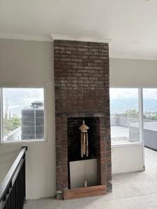 ein gemauerter Kamin in einem Wohnzimmer mit Fenstern in der Unterkunft Prabu Villa in Batu