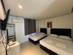 een slaapkamer met twee bedden en een flatscreen-tv bij Pattaya inn hotel in Pattaya South
