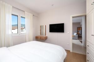 a white bedroom with a bed and a flat screen tv at The 764 Residence - Kalavryta Town center in Kalavrita +8 photos
