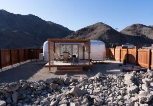 an rv parked in front of some rocks and mountains at Nomad By Sharjah Collection in Kalbā