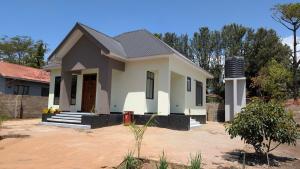 een klein wit huis in een tuin bij Danshome in Moshi