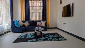 een woonkamer met een blauwe bank en een kleed bij Danshome in Moshi