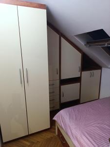 een slaapkamer met witte kasten en een bed bij Apartman 32 in Inđija