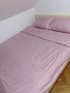 een bed met een paars dekbed in een kamer bij Apartman 32 in Inđija