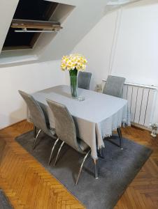 een eettafel met stoelen en een vaas met bloemen bij Apartman 32 in Inđija