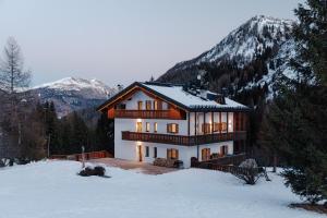 una casa nella neve con montagne sullo sfondo di Appartamento Aurone ad Arabba