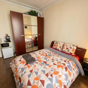 een slaapkamer met een bed met een oranje en grijs dekbed bij A spacious room in a strategic area in Montrouge