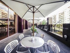 un tavolo con sedie e un ombrellone in un patio di Mercure Carlton Rioja a Logroño