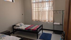 een kleine slaapkamer met een bed en een raam bij Danshome in Moshi