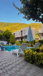 2 ligstoelen en een parasol naast een zwembad bij Ali Baba Butik Otel in Gündoğdu
