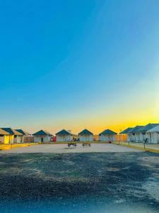 eine Gruppe von Hütten mit Sonnenuntergang im Hintergrund in der Unterkunft Stayguru Patgar Tent in Dhordo