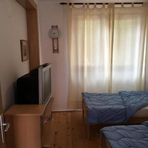 a room with a television and a bed and a clock at Feel like home guest house in Sarajevo