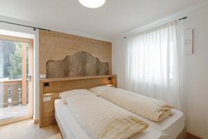 een slaapkamer met een bed met een houten hoofdeinde en een raam bij Appartamento Piz Boe' in Arabba