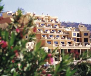 a large building with people sitting on the balconies of it at Grand Hotel Gozo in Għajnsielem