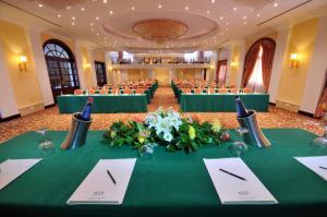 a banquet hall with green tables and chairs at Grand Hotel Gozo in Għajnsielem
