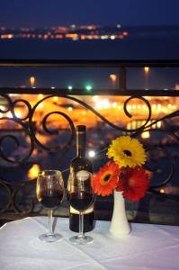 a table with two glasses of wine and a vase with flowers at Grand Hotel Gozo in Għajnsielem