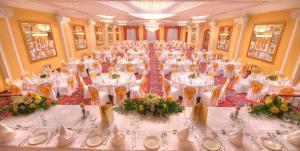 a large banquet hall with white tables and chairs at Grand Hotel Gozo in Għajnsielem
