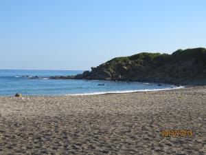 a sandy beach with rocks in the water at casa verdemare in Cefalù
