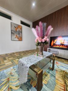 un salon avec un vase de fleurs et une télévision dans l'établissement MakutuBnB, Nadi, à Nadi