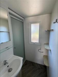 un bagno bianco con un lavandino e una finestra di Mobil home Oasis Les Palmiers a Valras-Plage